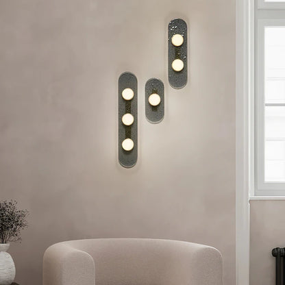 three bulb sconce viewed from the side mounted on a light grey wall
