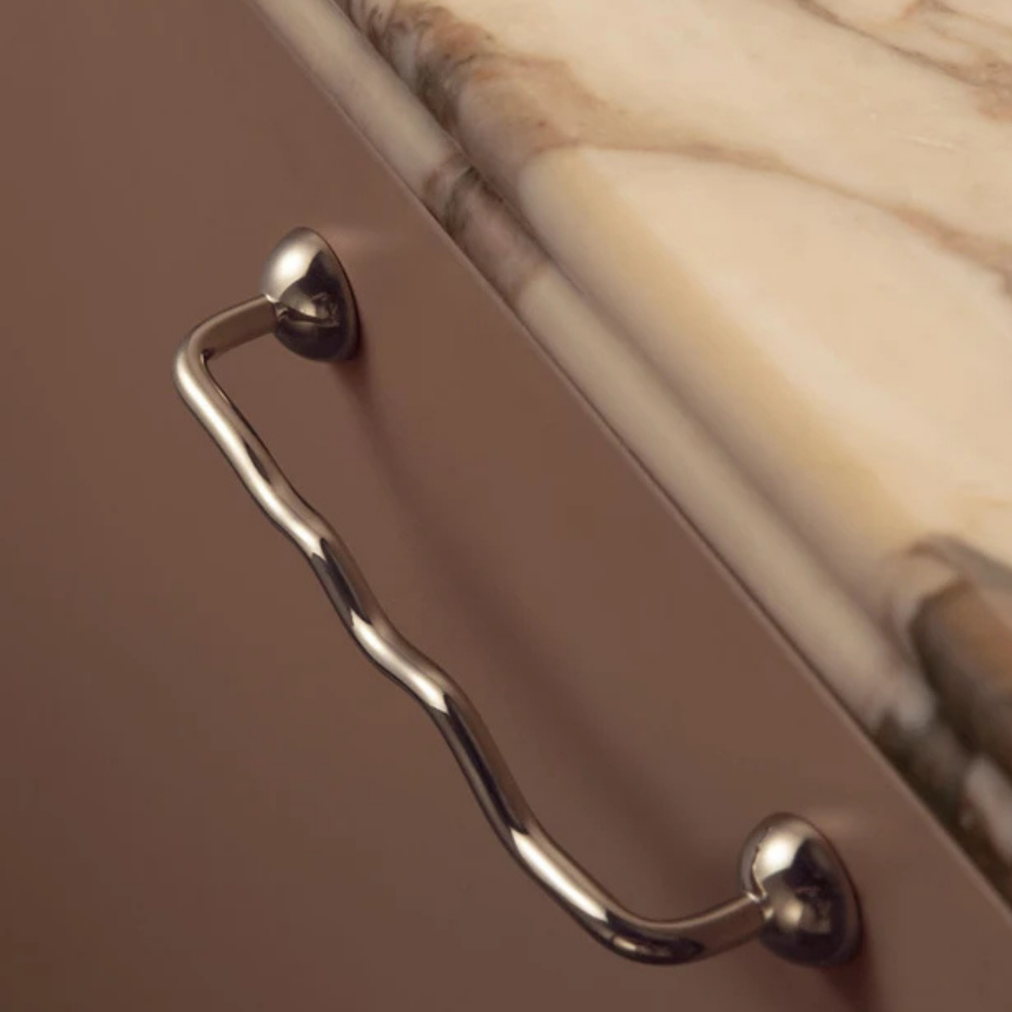 Curved stainless steel handle installed under a marble countertop