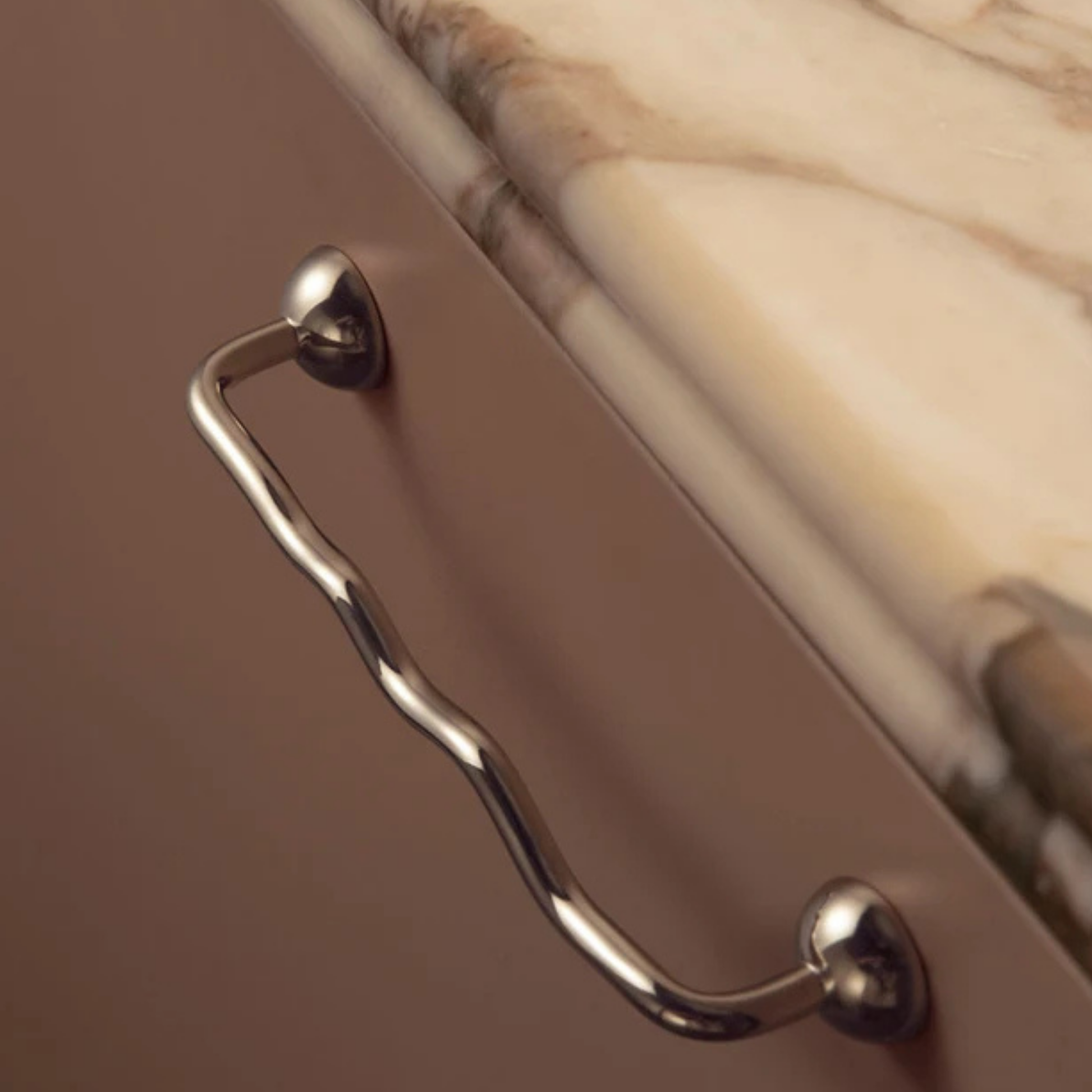 Curved stainless steel handle installed under a marble countertop
