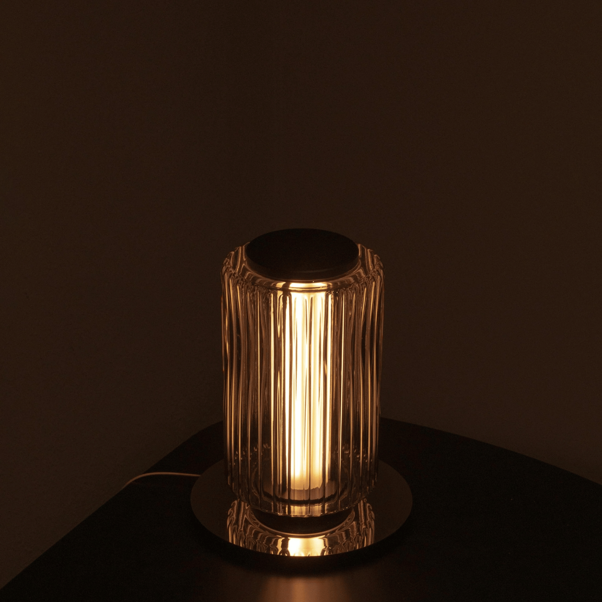 Decorative lamp with ribbed glass shade on a dark surface
