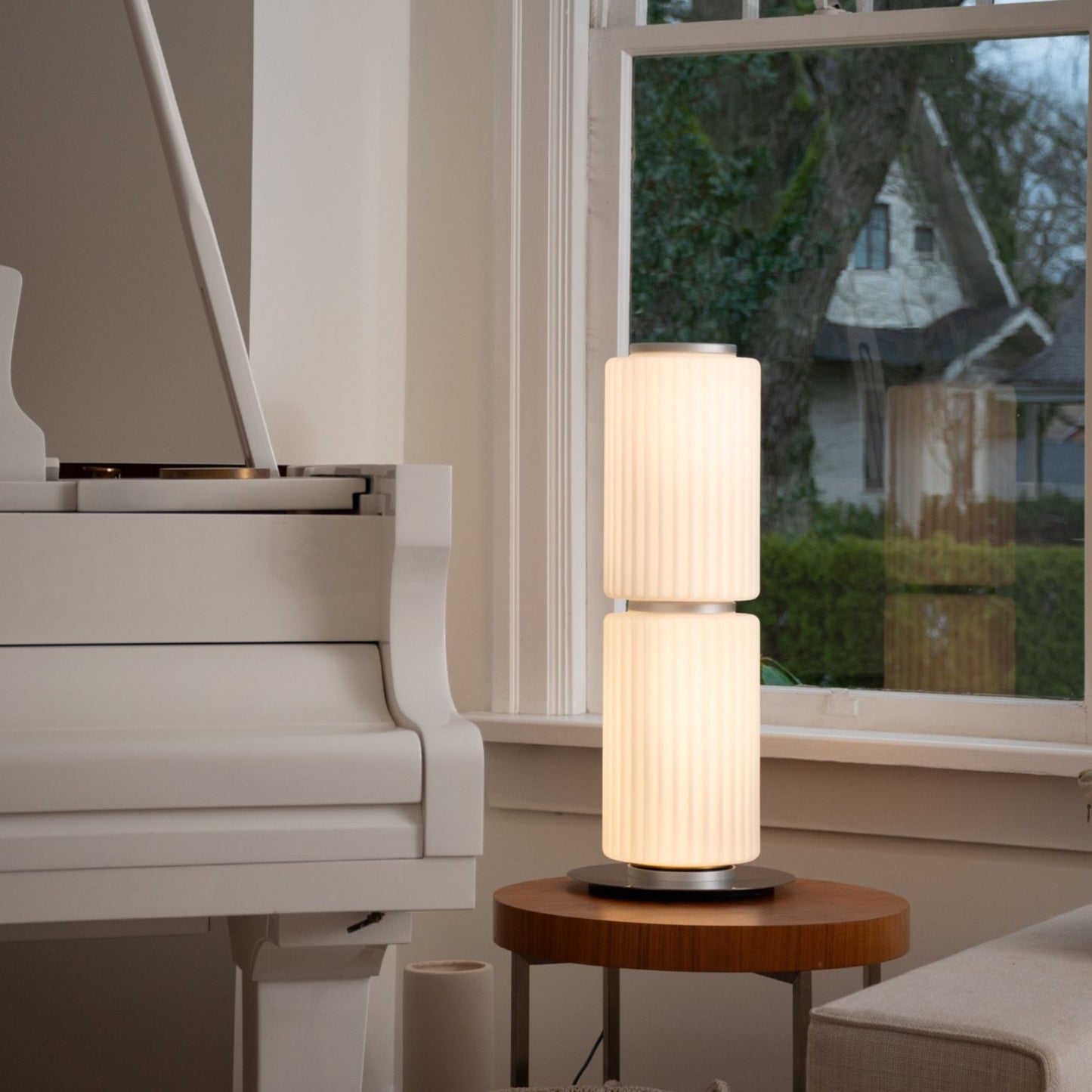 Warm-lit ribbed-glass lamp on a glass dining table in a dark interior.