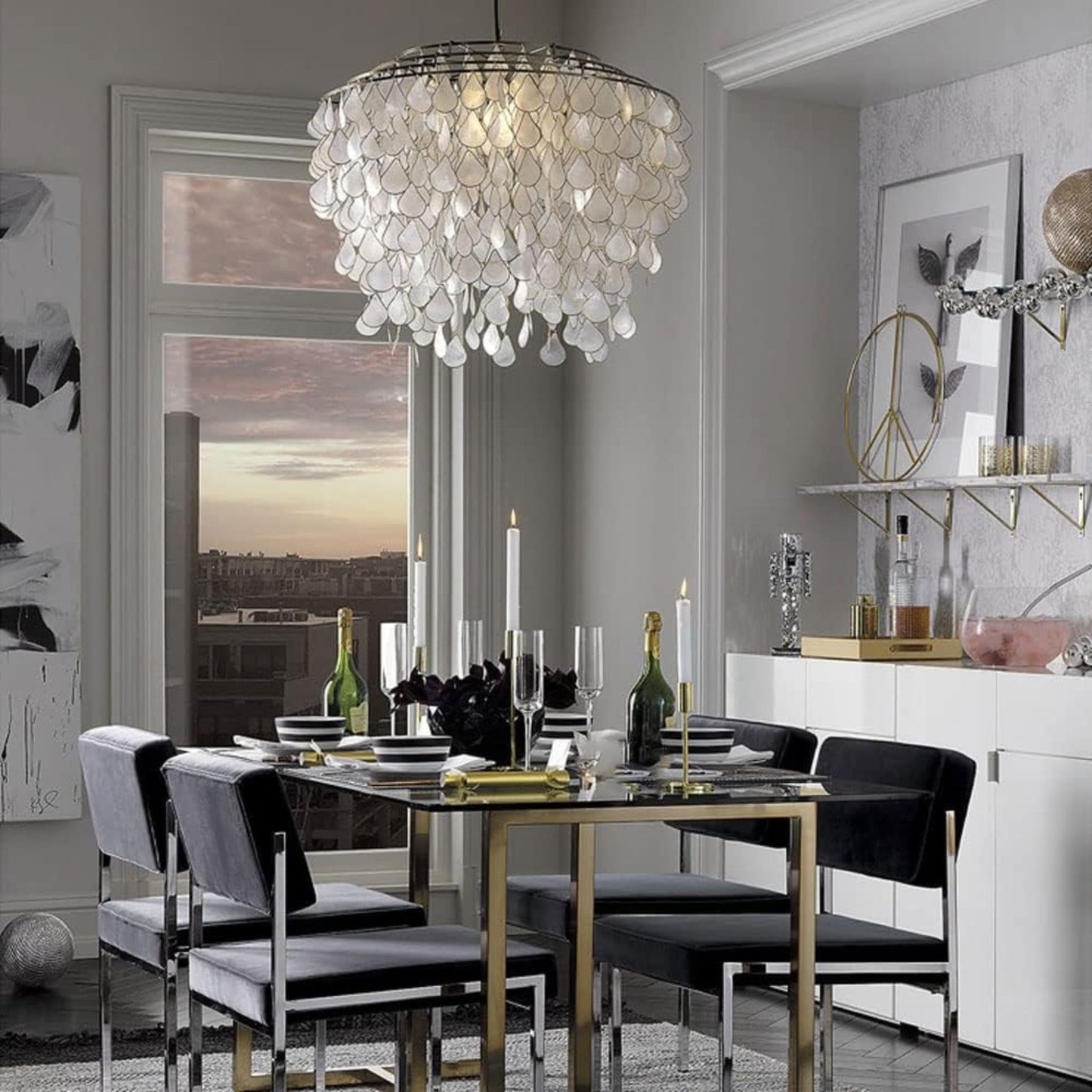 A chic dining room with a glass dining table, velvet chairs, a pendant light, and a view of the sunset through the window.