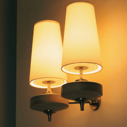 Wall-mounted lamp with two illuminated lampshades on a dark background
