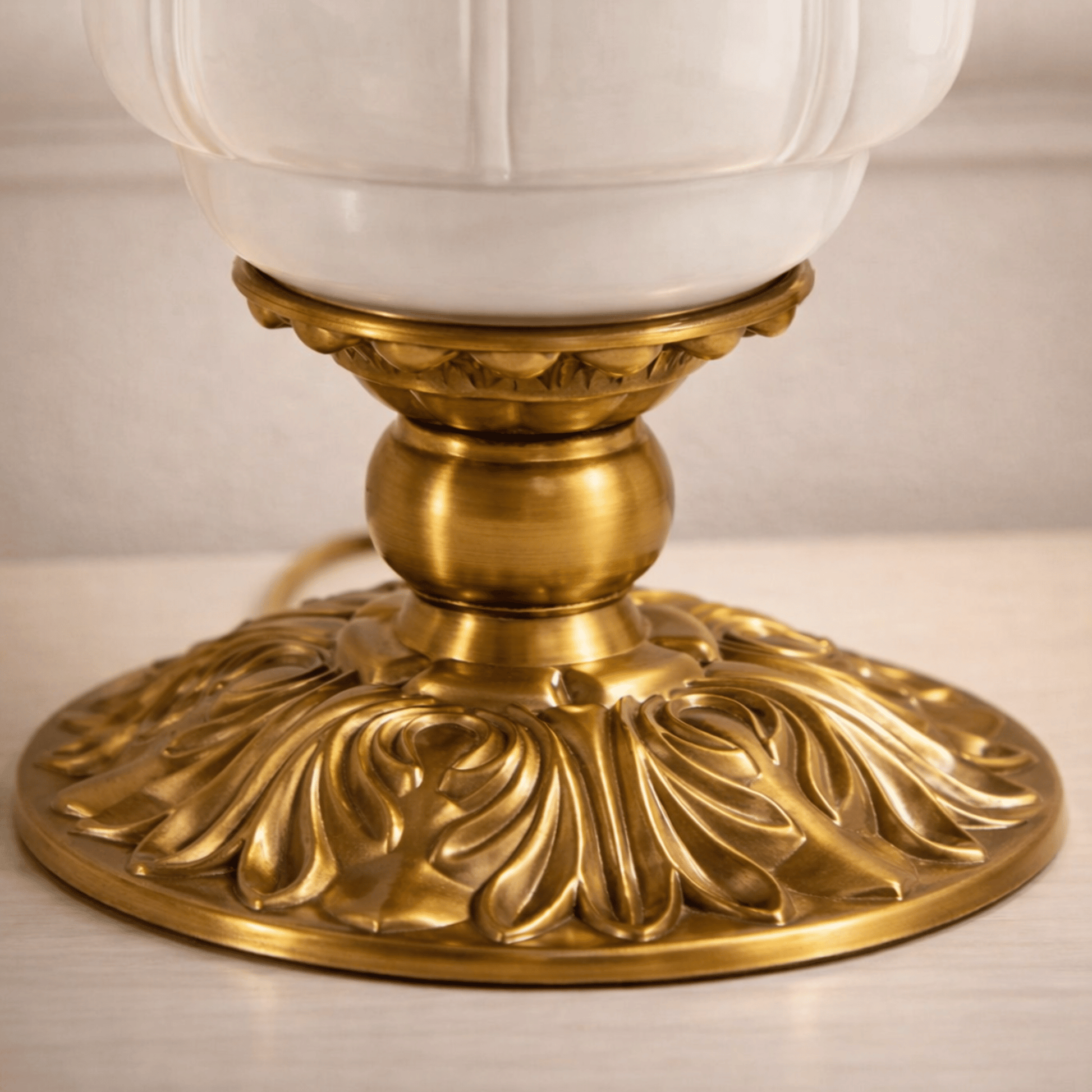 Decorative lamp with gold base and white glass shade on a neutral background