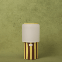 Table lamp with striped base and beige shade on a green background