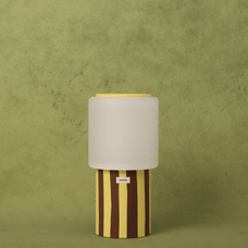 Table lamp with striped base and beige shade on a green background
