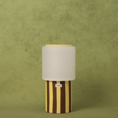 Table lamp with striped base and beige shade on a green background