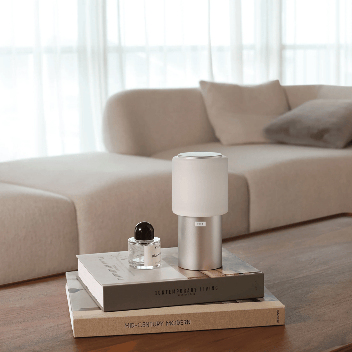 Small lamp on a stack of books with a beige sofa in the background