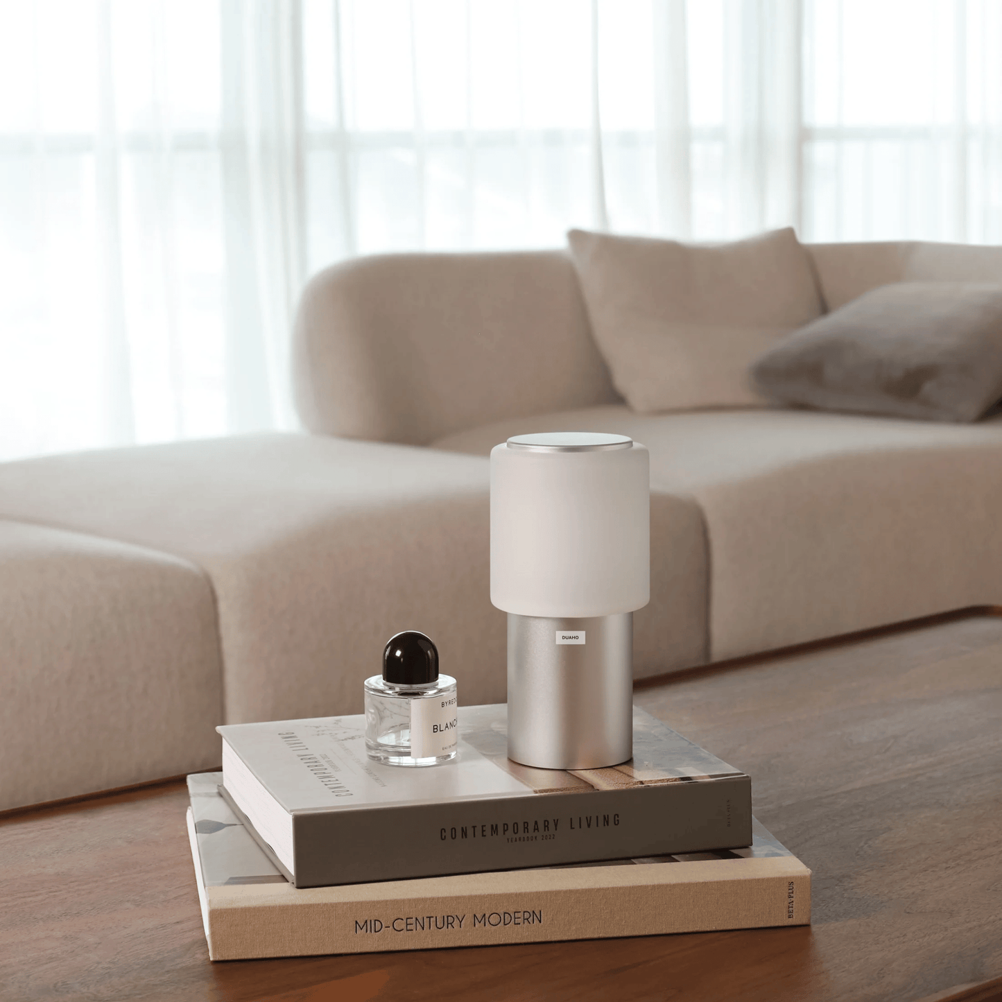 Small lamp on a stack of books with a beige sofa in the background