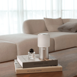 Small lamp on a stack of books with a beige sofa in the background
