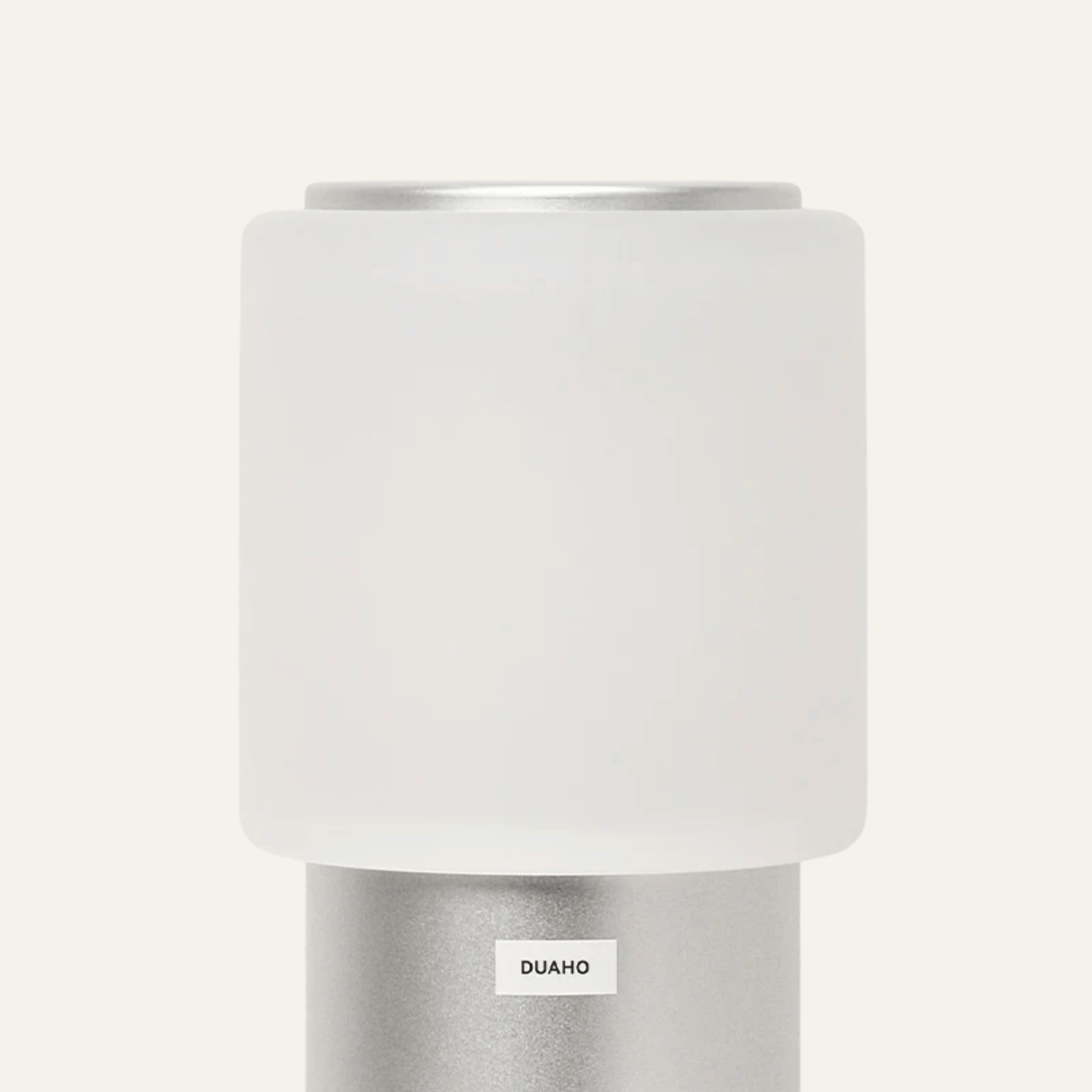 White cylindrical lamp with silver base on a white background