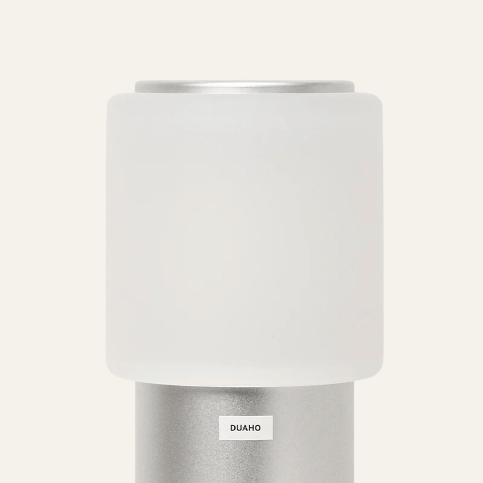 White cylindrical lamp with silver base on a white background