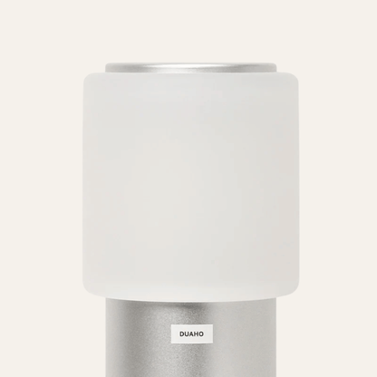 White cylindrical lamp with silver base on a white background