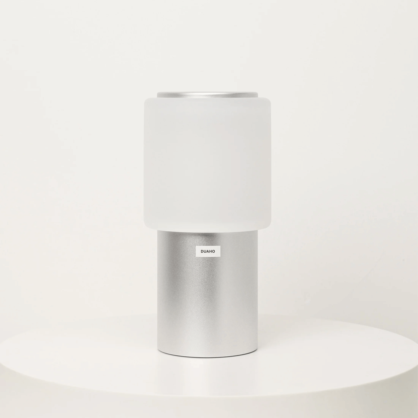 White cylindrical container with silver base on a white background