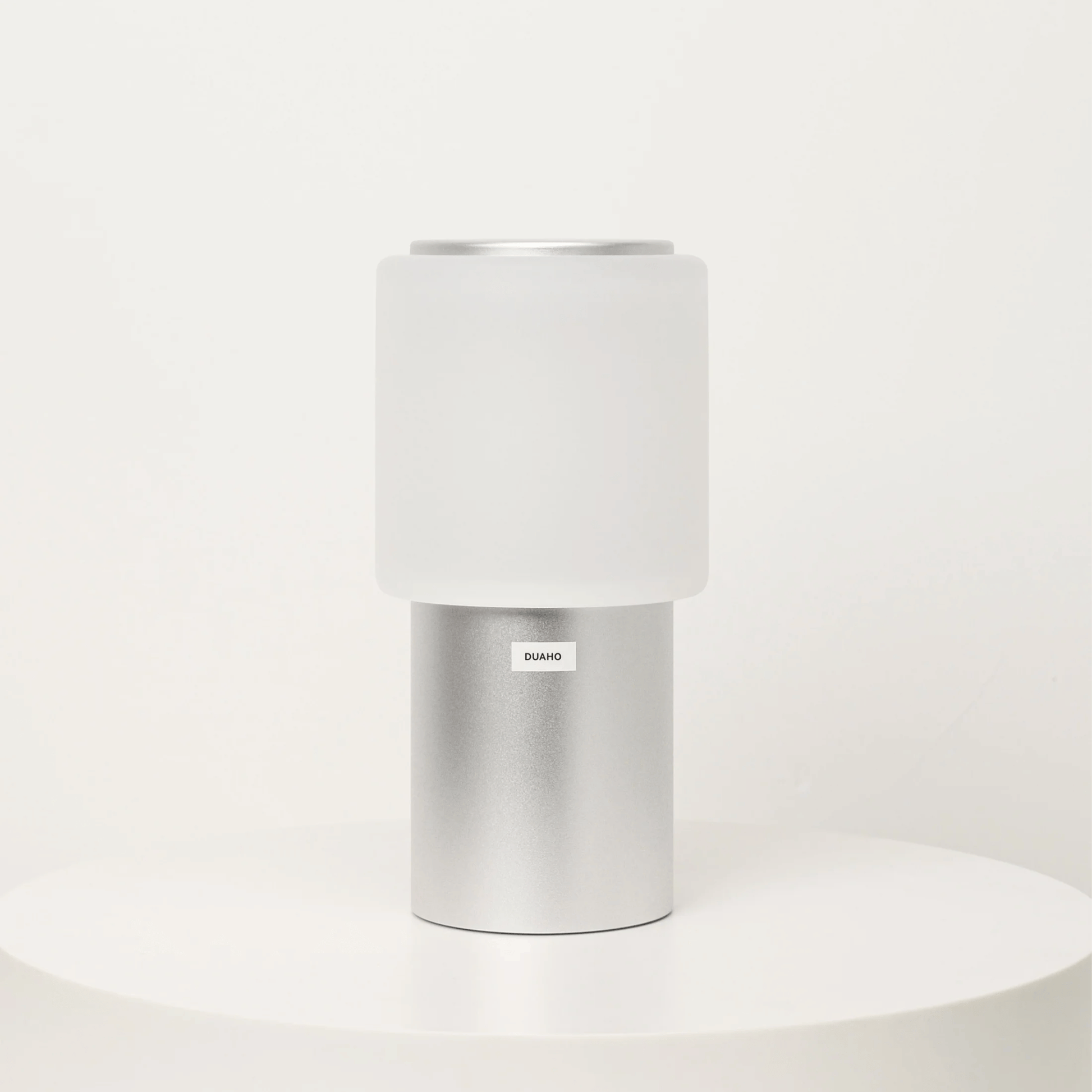 White cylindrical container with silver base on a white background