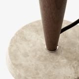 Close-up of a wooden leg with a black cord on a beige marble base.