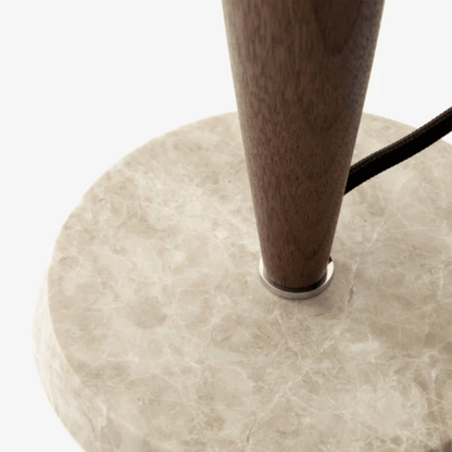 Close-up of a wooden leg with a black cord on a beige marble base.