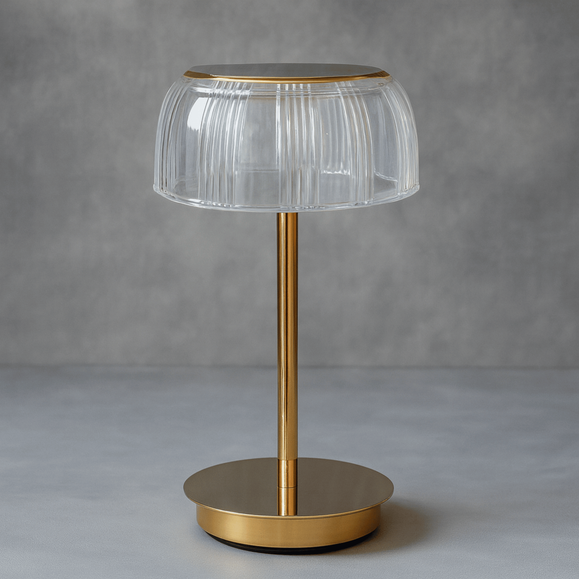 Table lamp with clear glass shade and gold base on a gray background