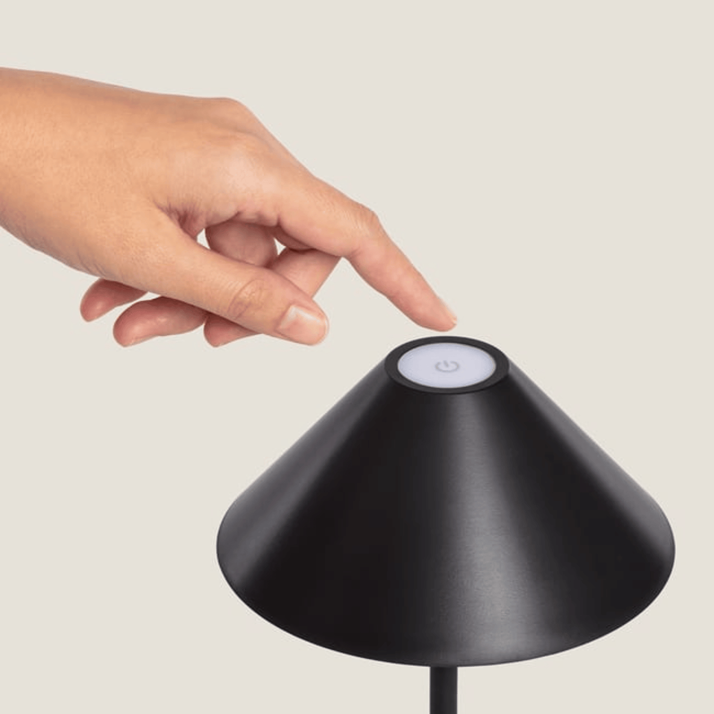 Hand touching a black lampshade with a light sensor on a neutral background