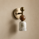 Wall-mounted light fixture with brass and marble design on a beige wall