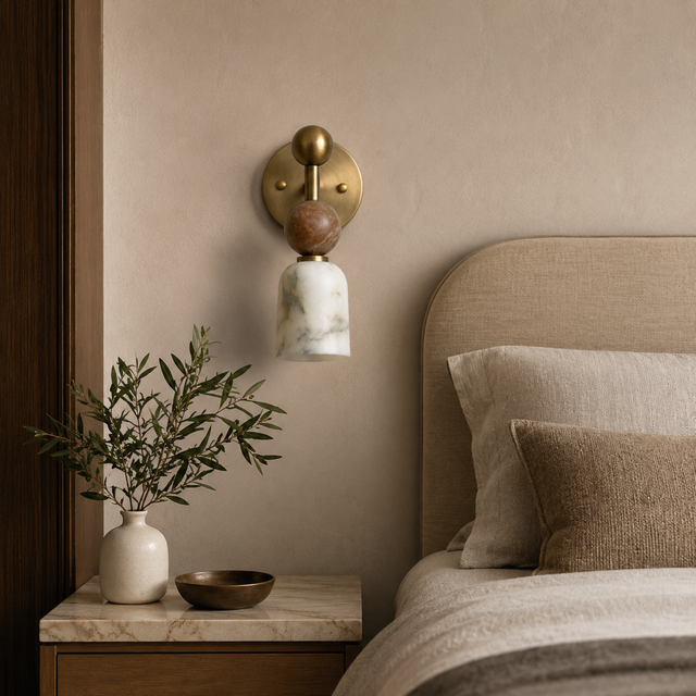 Decorative wall sconce above a bed with pillows and a plant on a nightstand.