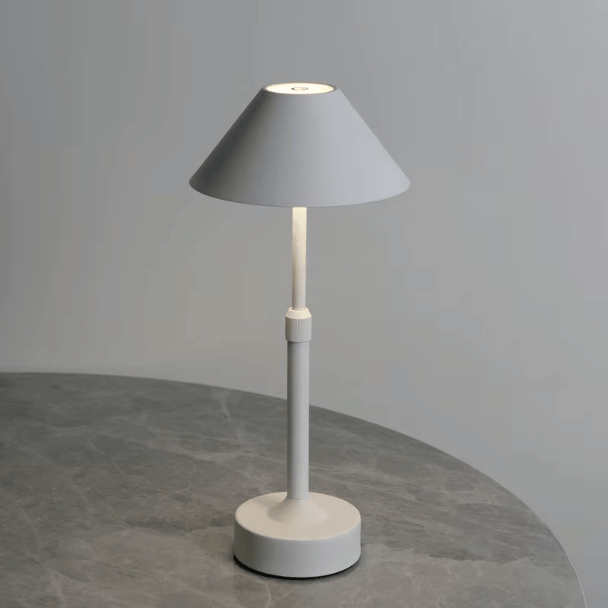 Modern table lamp with gray shade and white base on a gray surface.