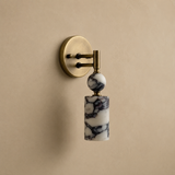 Wall sconce with marble base and brass fixture on a beige wall