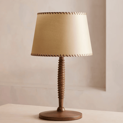 Table lamp with a wooden base and beige fabric shade on a neutral background