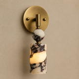 Wall sconce with marble-like design and gold fixture on a beige wall
