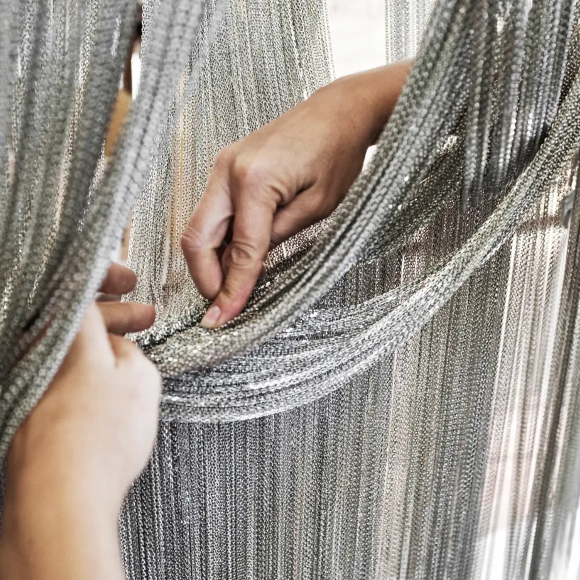 Close-up of hands holding a silver chainmail garment