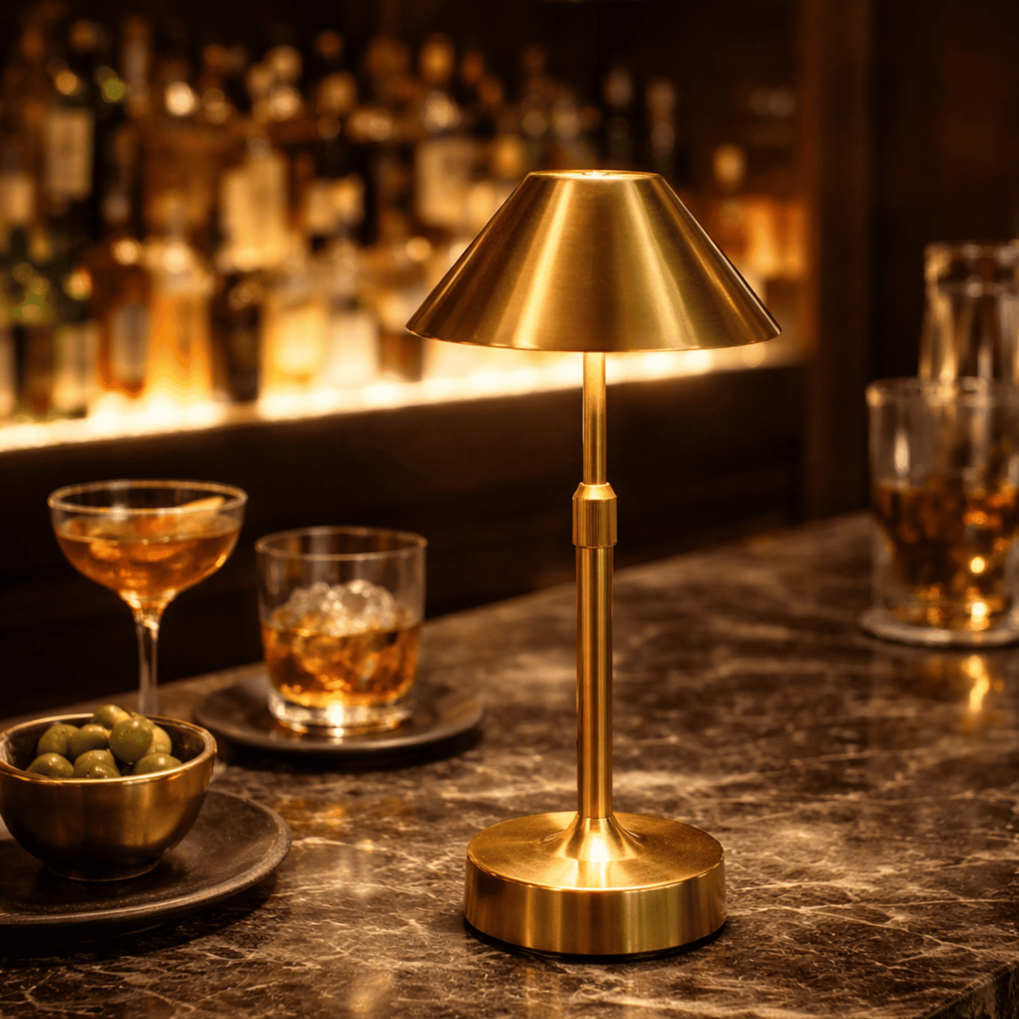 Gold lamp on a bar counter with drinks and snacks in the background
