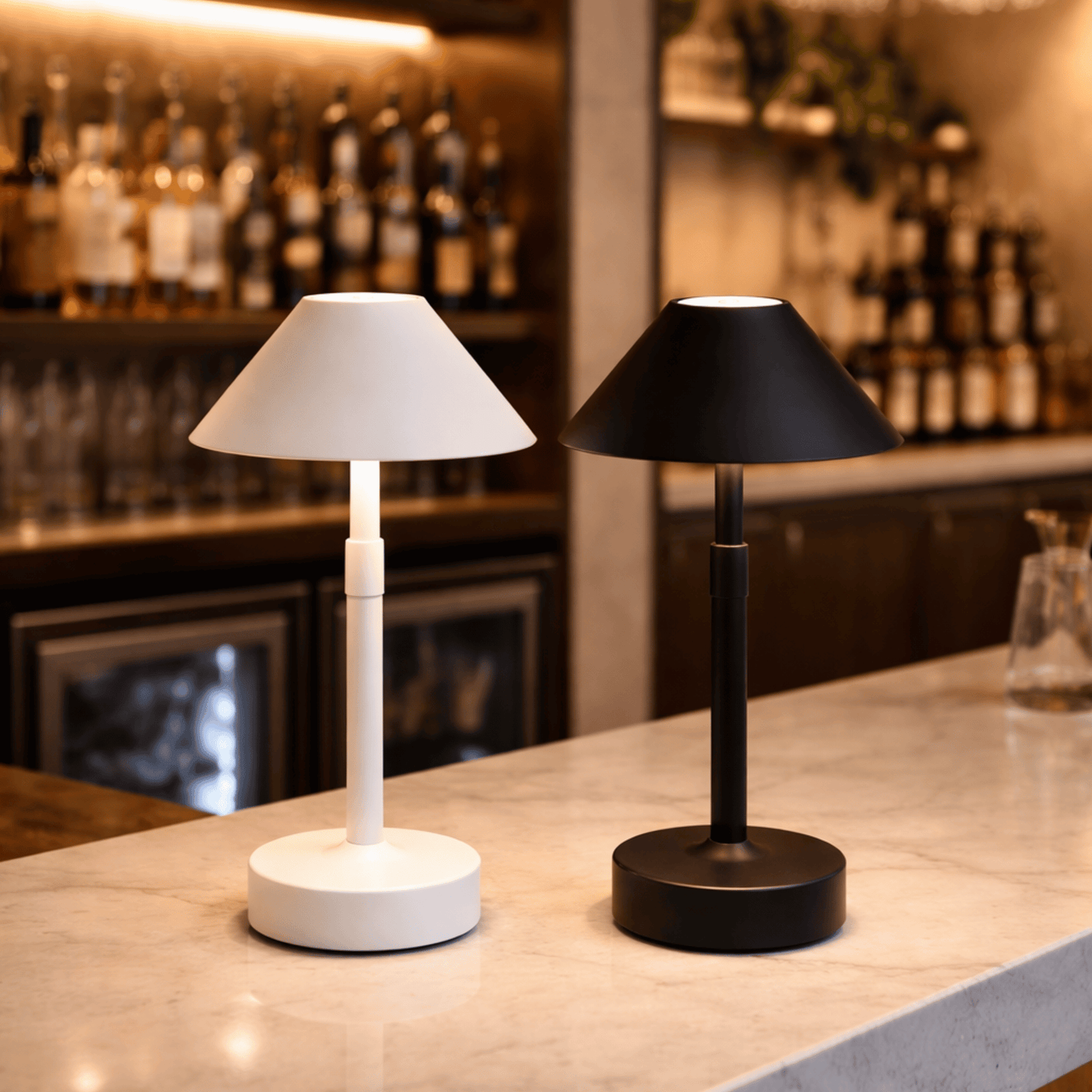 Two table lamps, one white and one black, on a bar counter with bottles and glasses in the background.