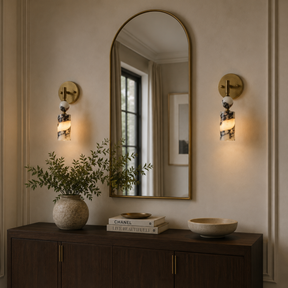 Decorative wall mirror with sconces and a cabinet in a room setting.