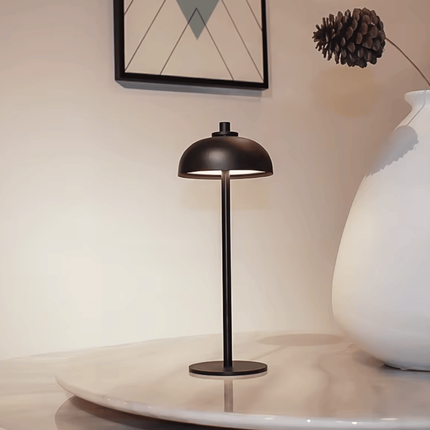 Black table lamp on a marble surface with a white vase and decorative item in the background.