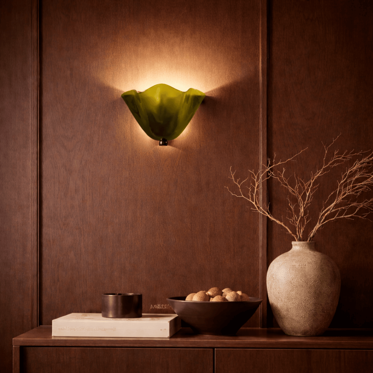 Decorative wall sconce with a green glass shade on a brown paneled wall.