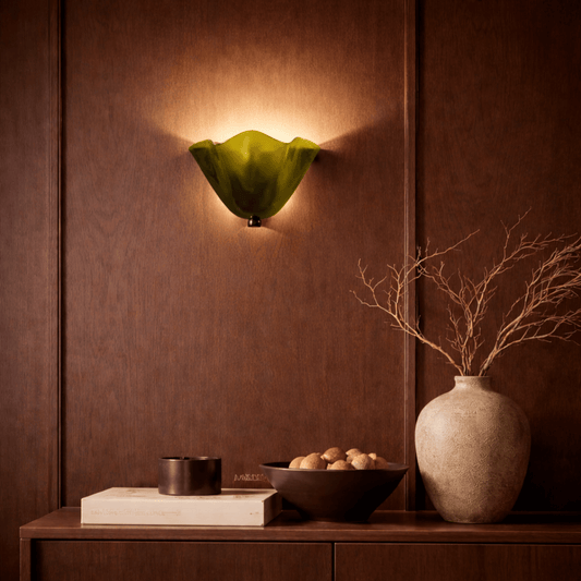 Decorative wall sconce with a green glass shade on a brown paneled wall.