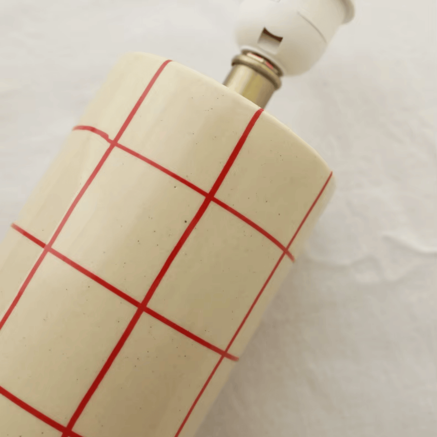 Ceramic flask with red grid pattern on a white background