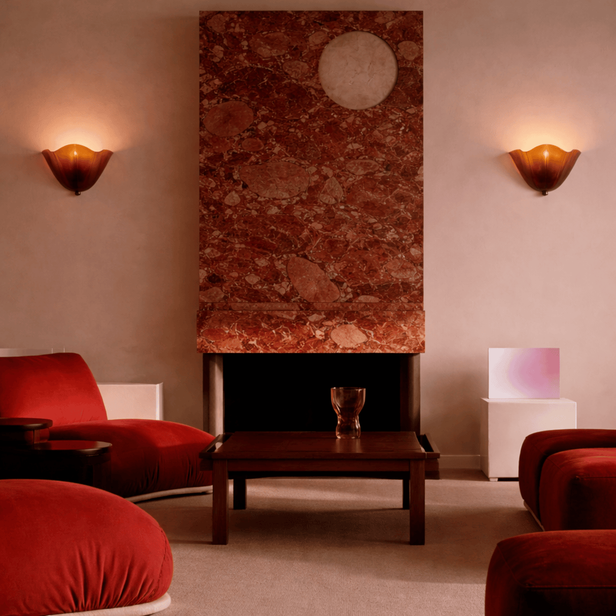 Modern living room with red chairs, a wooden coffee table, and a decorative wall piece.