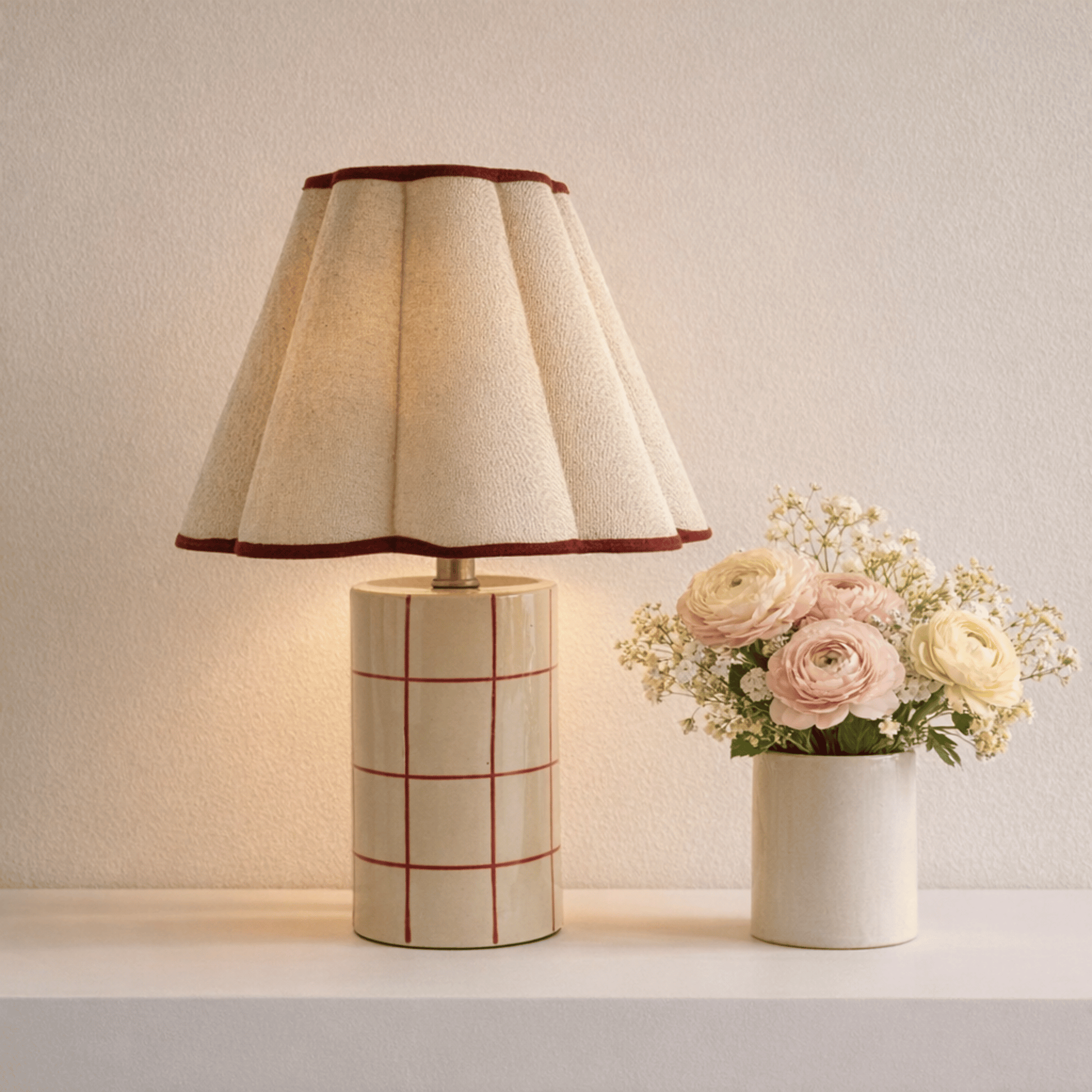 Table lamp with a checkered base and a vase of flowers on a neutral background