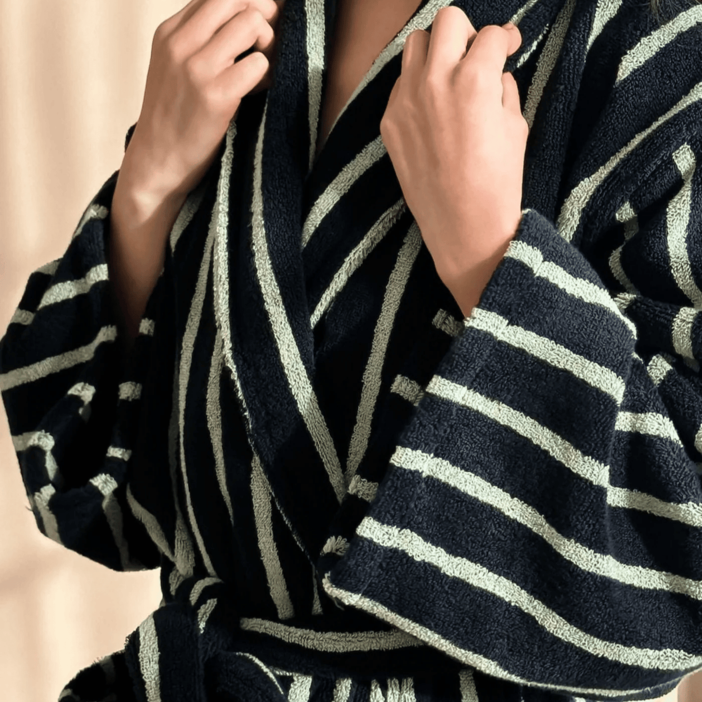 Navy blue and white striped robe being worn by a person against a beige background