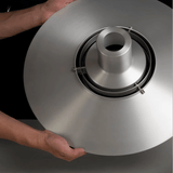 Metallic lampshade held by a person against a dark background