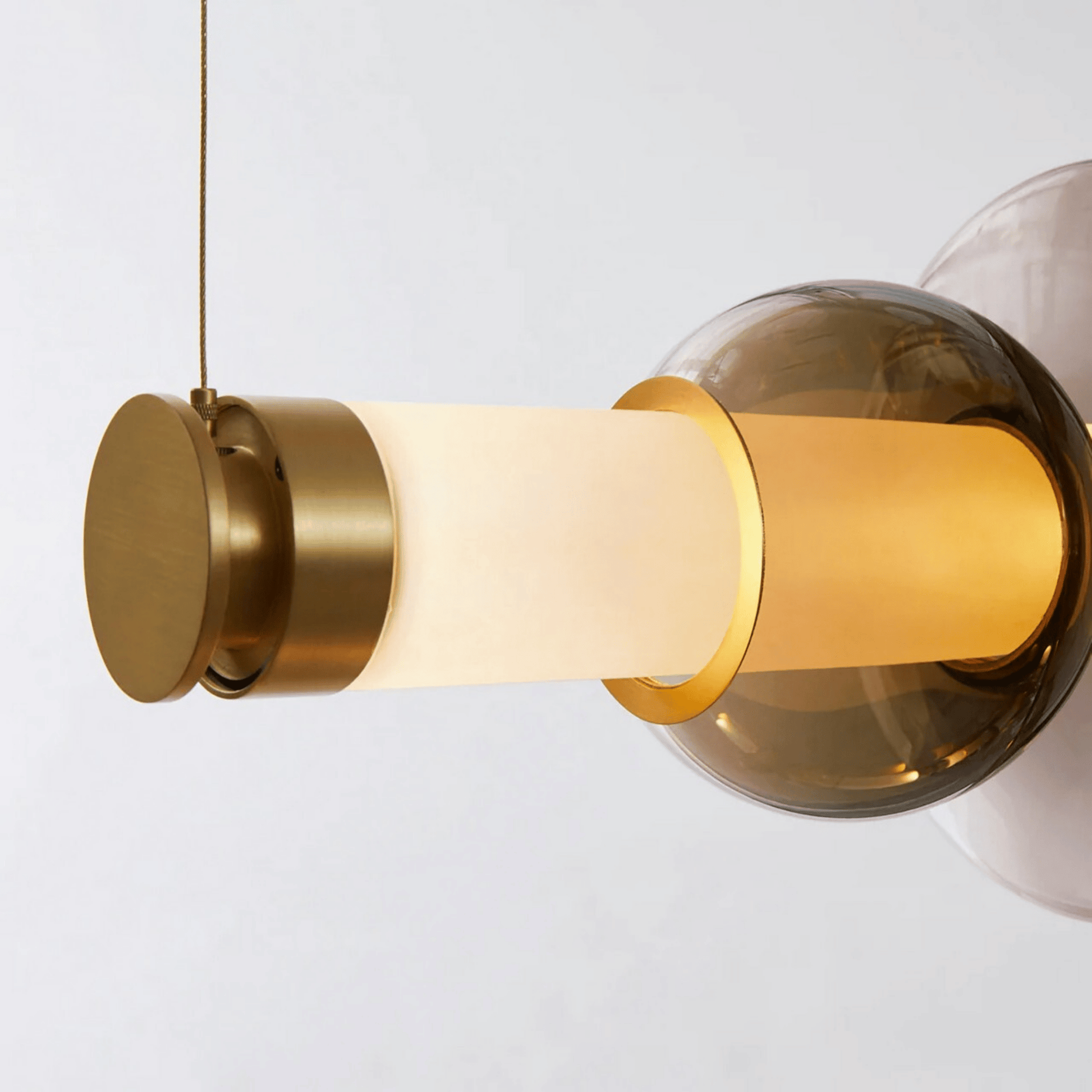 Modern pendant light with gold and glass design on a white background