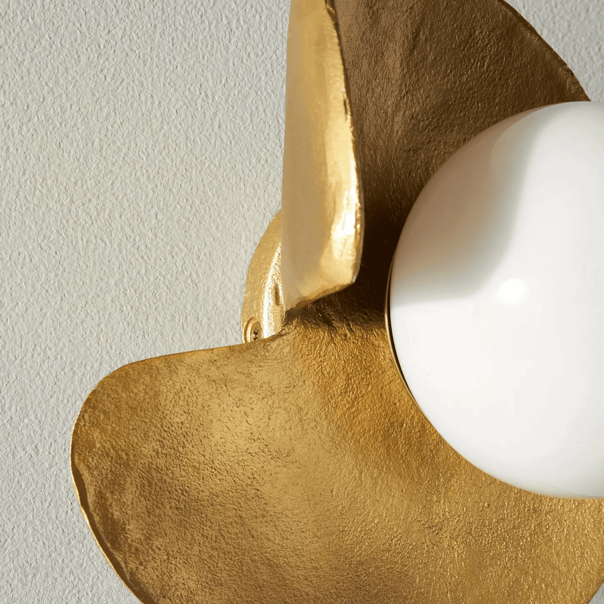 Gold and white wall sconce against a light gray wall