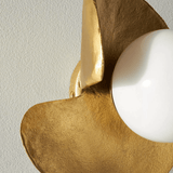 Gold and white wall sconce against a light gray wall
