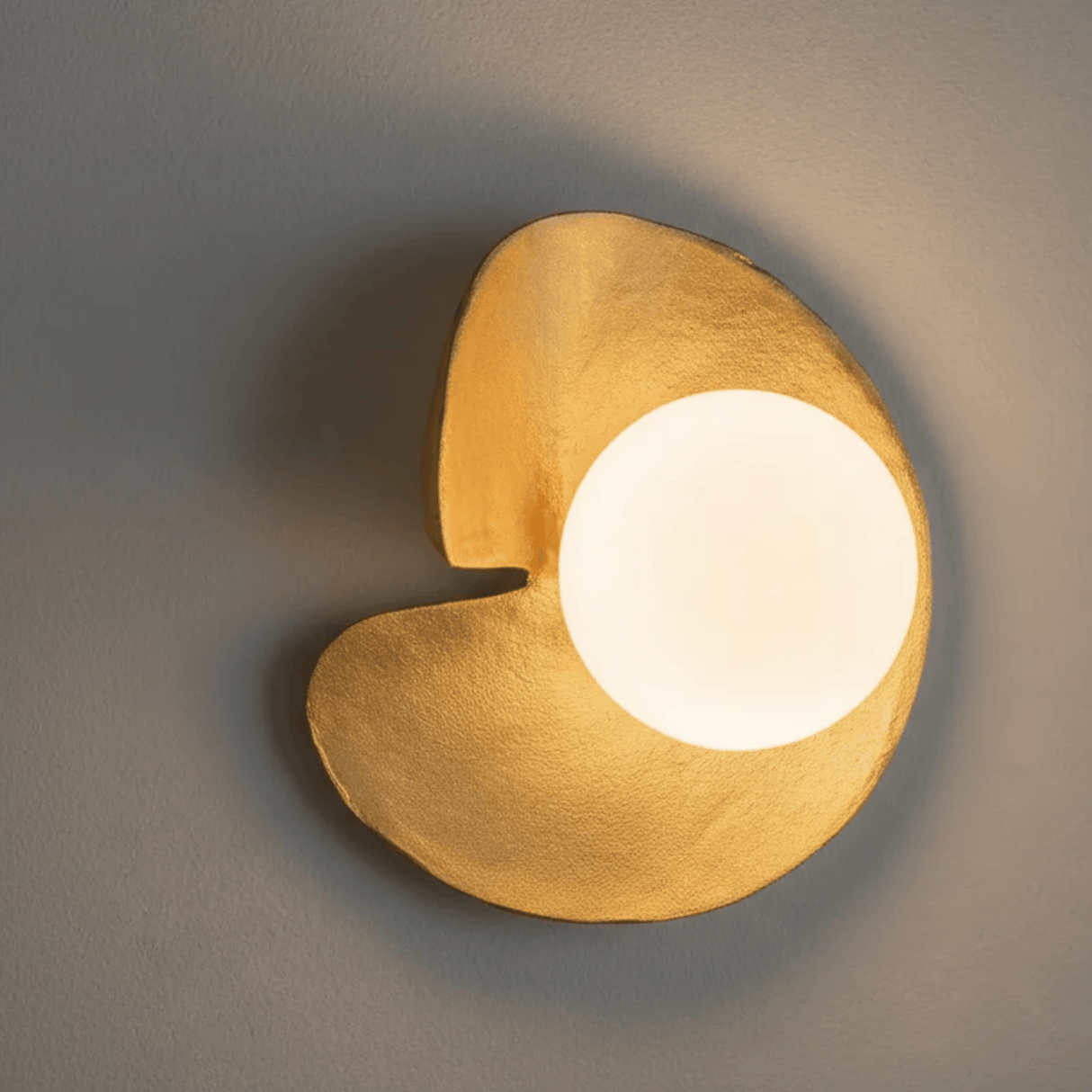 Modern wall light fixture with a warm glow on a neutral background