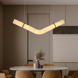 Modern pendant light hanging above a dining table with chairs in a stylish interior setting.