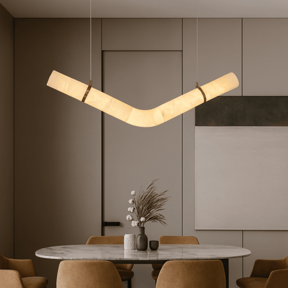 Modern pendant light hanging above a dining table with chairs in a stylish interior setting.