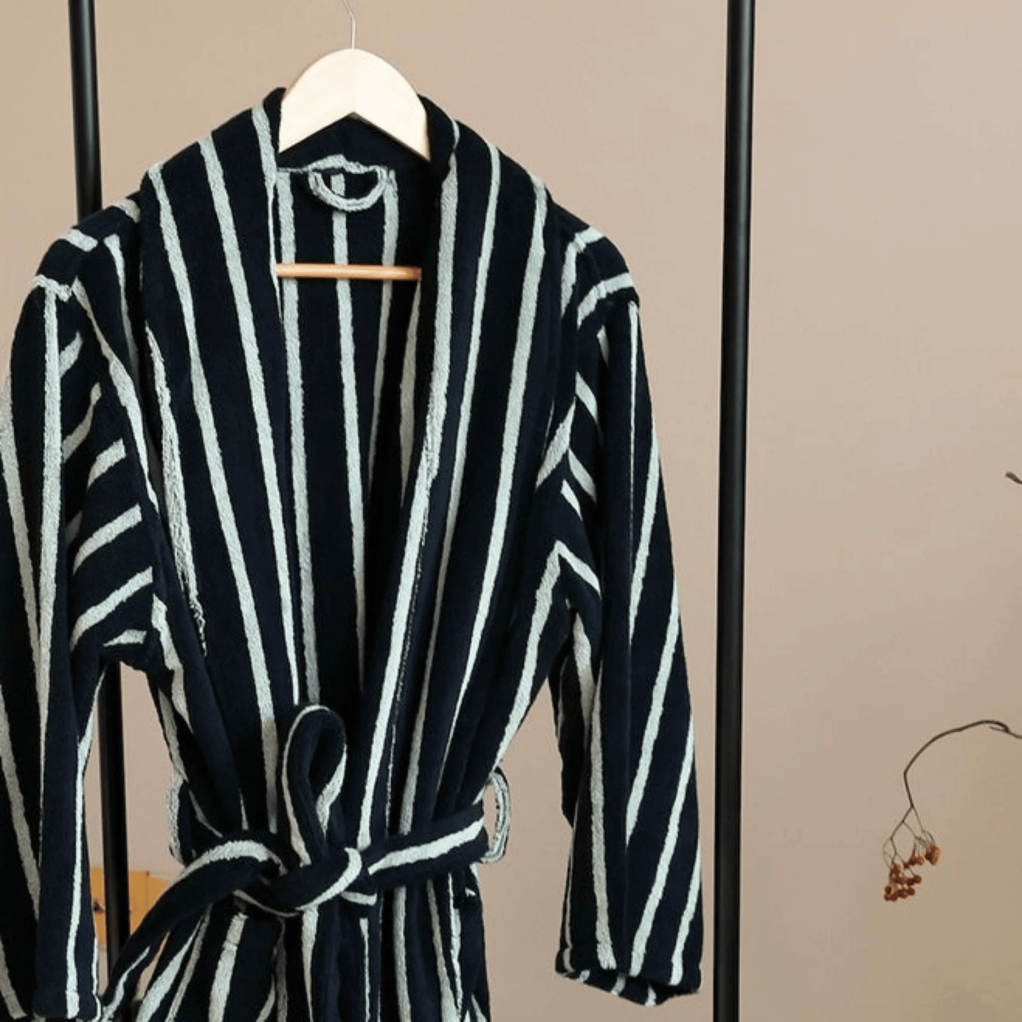 Black and white striped robe on a hanger against a beige wall.
