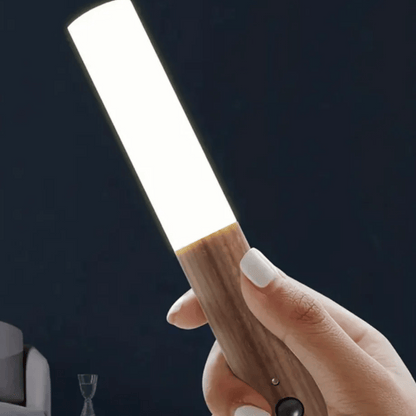 Hand holding a wooden tool against a dark background