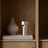 Silver lamp and textured vase on a wooden shelf